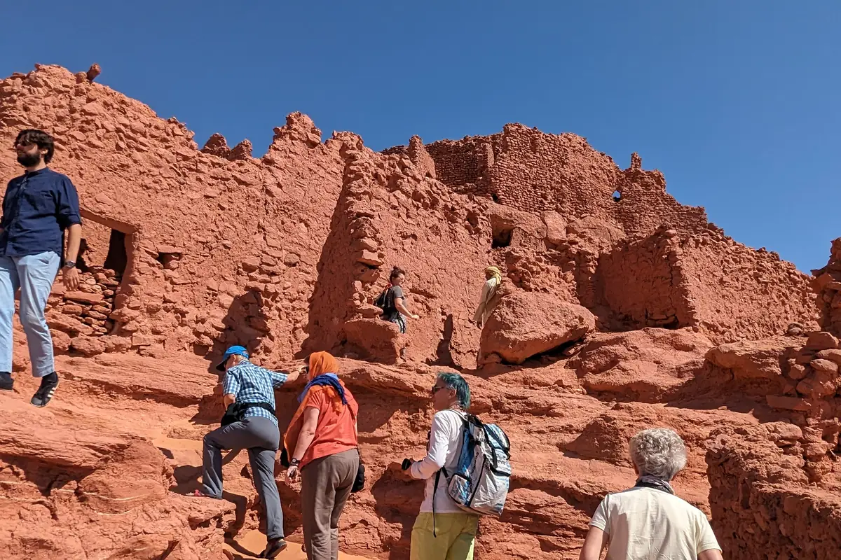Travellers climbing the red earth walls of the old ksar at Timimoun
