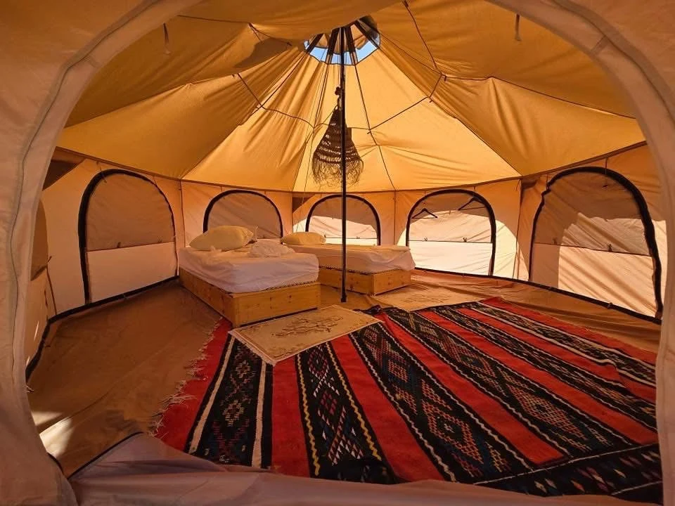 Inside a Tourago desert tent near Djanet: a made bed, rugs and a lantern