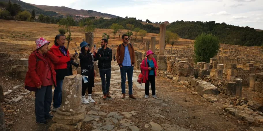 Tourago travellers standing among the stones of the Roman city of Djemila