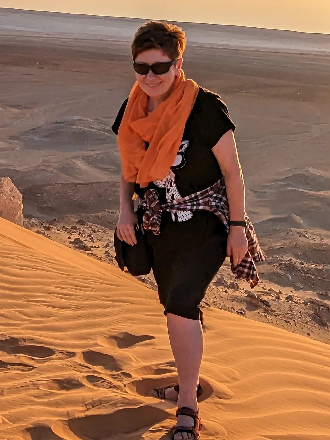 A traveller walking the dunes at El Menia, a scarf caught in the wind