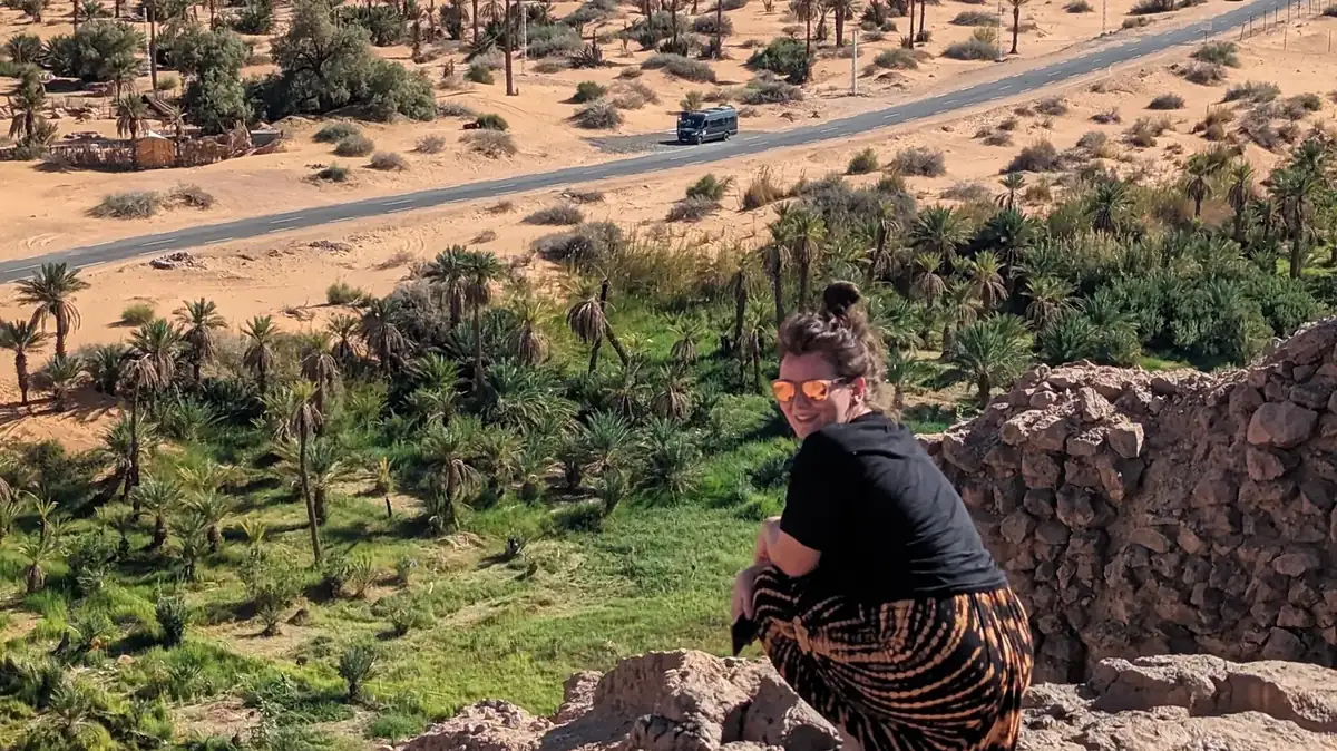 A traveller resting on a rock above the palm groves at Taghit