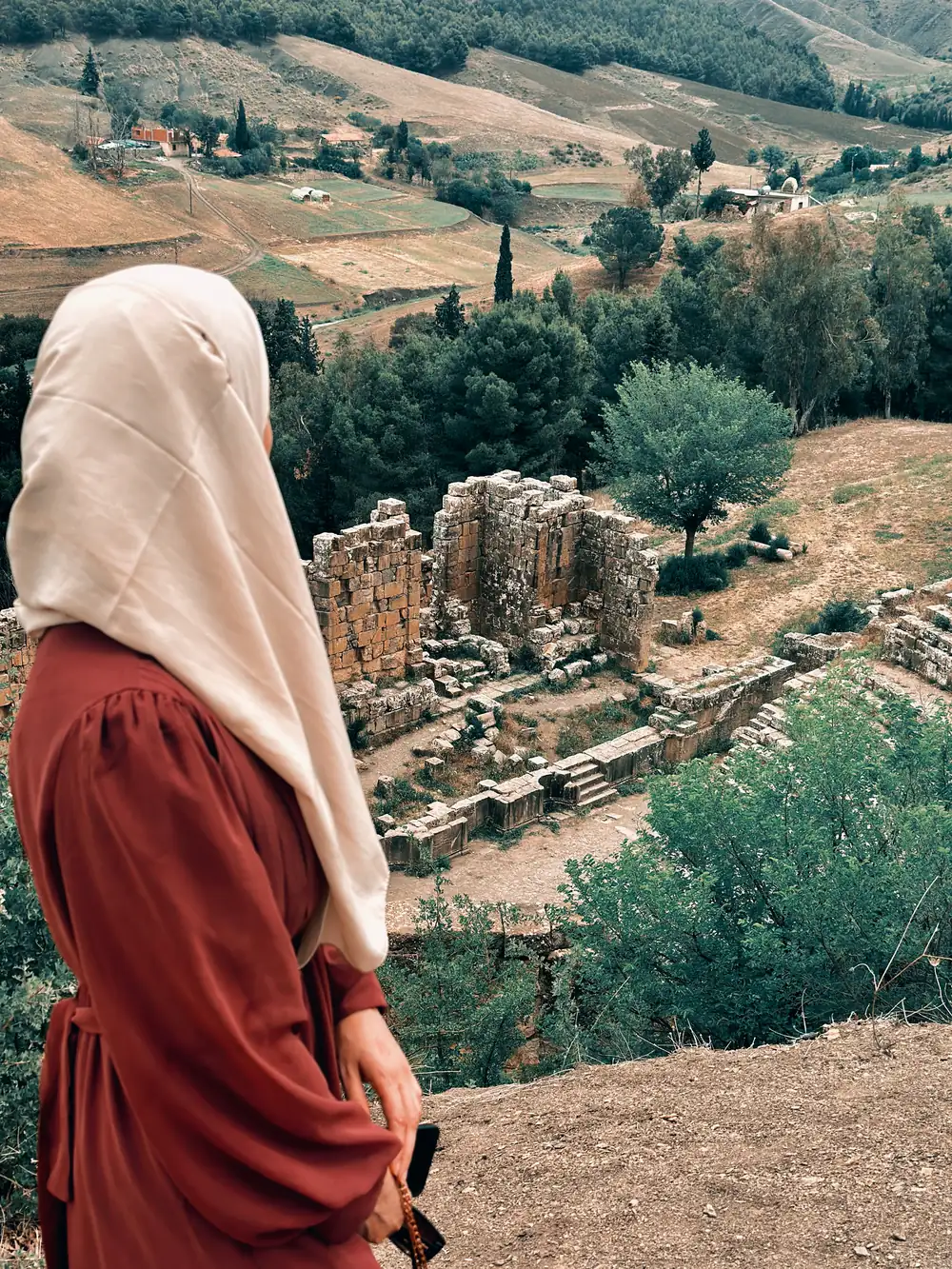 A traveller looking out over the Roman ruins and the valley at Djemila