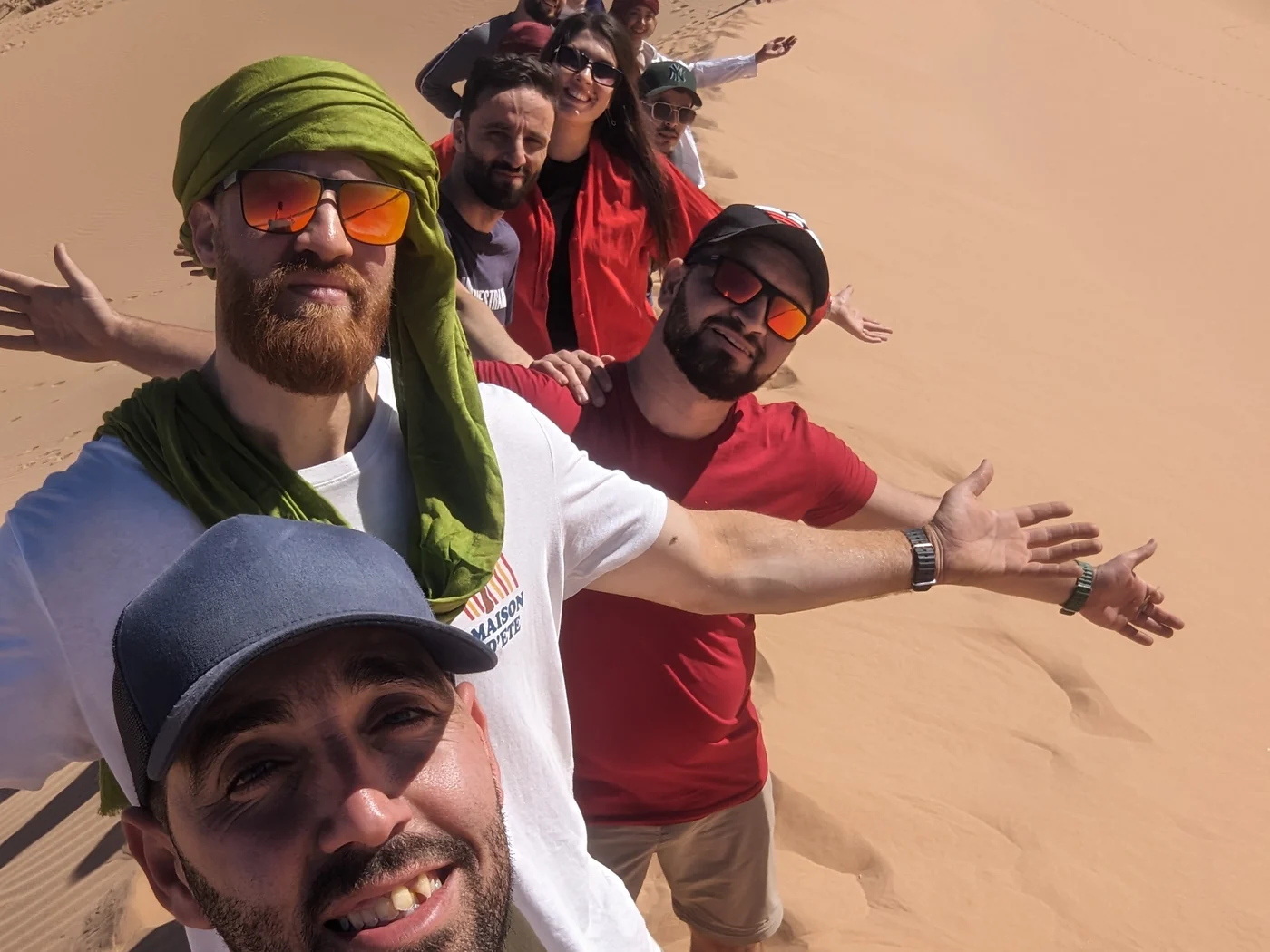 Tourago travellers on a dune at El Bayadh, arms wide